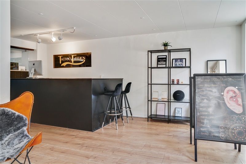 Piercingstudiet har et moderne og flot design med en høj og flot bord, høje stole, en plante og et sæt øre piercings