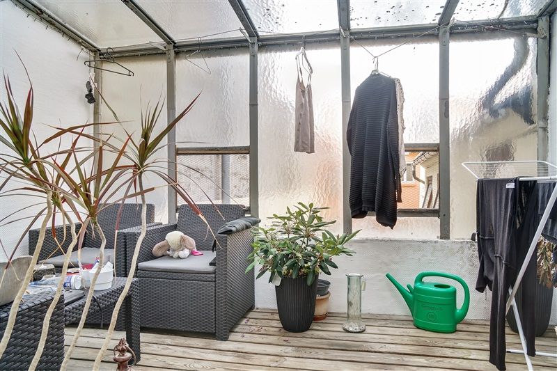 En have med to sæder, en blomsterpotte, et svansvande, tøj på vasketøjsstativ og en vandkande