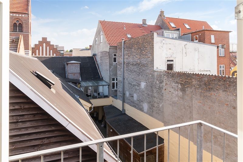 Balkon med udsigt over bygninger med røde tag og lyse vinduerne og træbalkonger og røde mursten