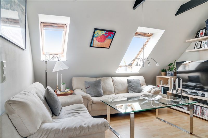 Lys stue med hvide vægge og to sovesofaer med grå pude, glasbord og moderne møbler