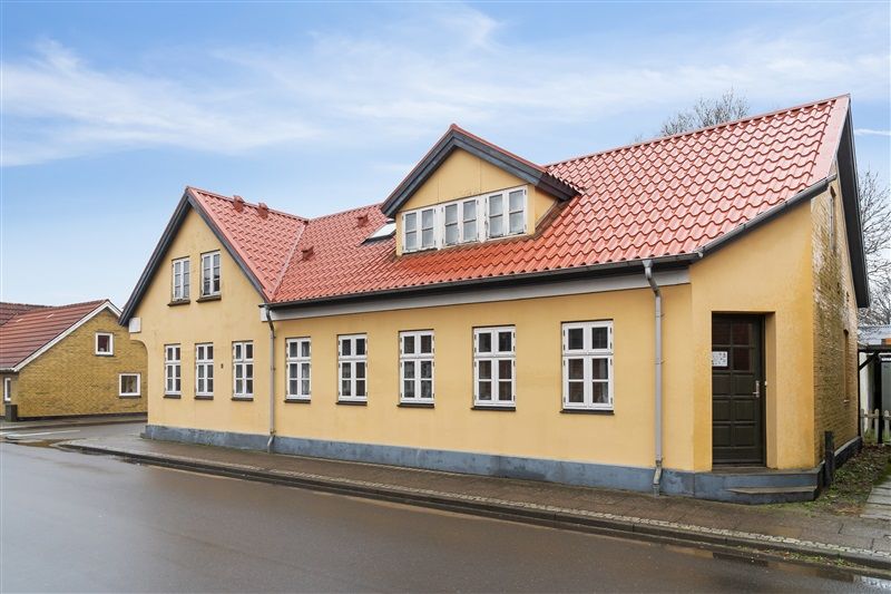 Gult hus med tegltag og hvide ruder ligger på Borgergade 12 i Skovlund, tæt på Ansager, og har 10,06% afkast