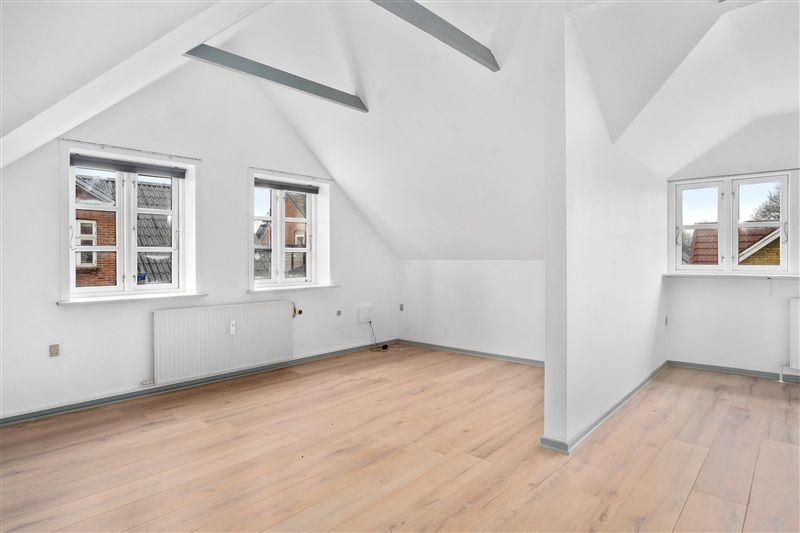 En nyrenoveret og fuldt møbleret lejlighed med tre vinduer, hvide vægge, lyse trægulve og radiatorer i Skovlund