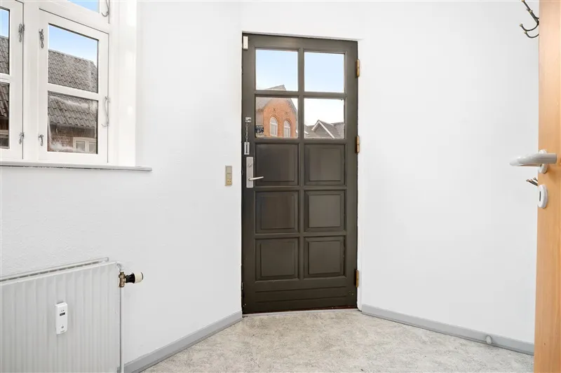 Lukket træindgangsdør med glasindsats og et radiator tæt ved døren