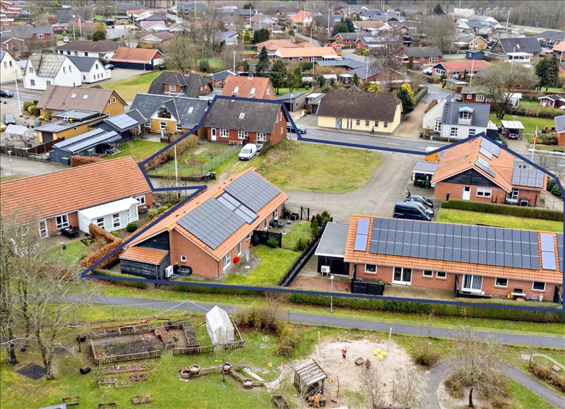 Flere huse med solceller og en legeplads, små veje og lyse, lyserøde huse