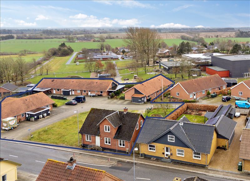 Rækkehuse med parkeringspladser og en bilparkeringsplads, solpaneler og husene med en grøn mark og en bus, der står parkeret