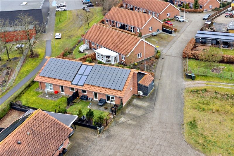 Moderne og velplejede rækkehuse med solpaneler på tagene og parkerede biler foran og bagved