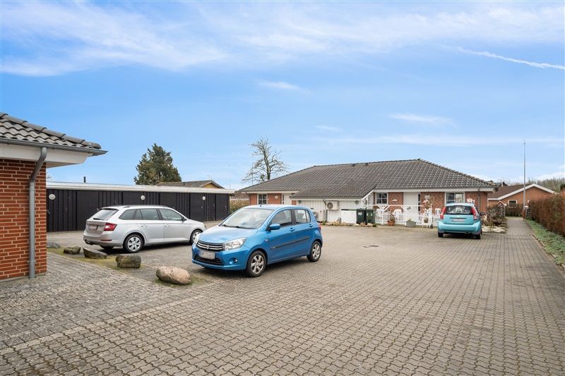 3 biler parkeret i garagen og på en parkeringsplads foran en bygning i Vorbasse