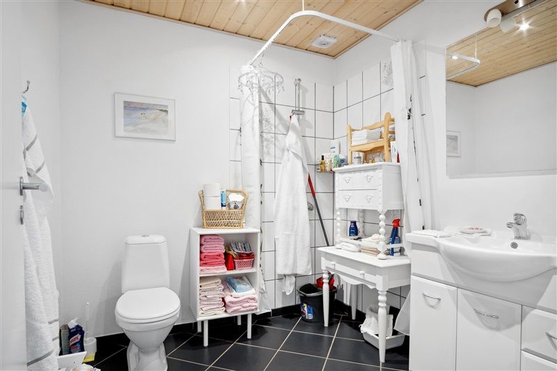 Rent og moderne badeværelse med toilet, håndvask og tøjstativ, samt håndklæder og sæbe.