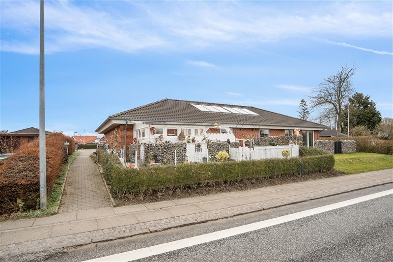 Rækkehus med solceller på taget og en indgangsvej foran et grønt anlæg