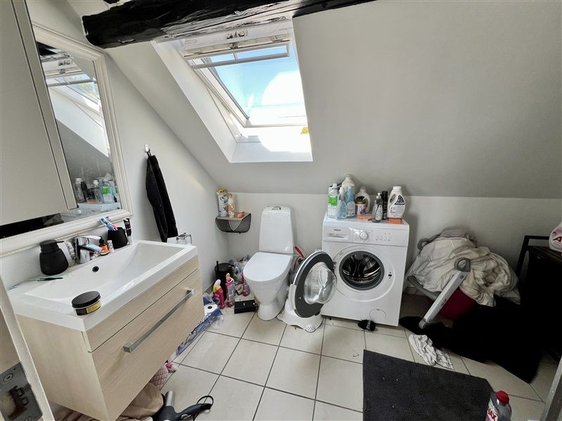 Bad med toilet, vask og vaskeri. Lys og luftige loftsværelse med tøjvask og toilet. Vindue og spejl i loftsrummet.