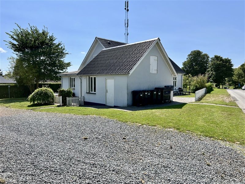 Moderne hvid villa med terrasse og græsplæne i Nørre Aaby, 2 sorte affaldscontainere og gitterhegn