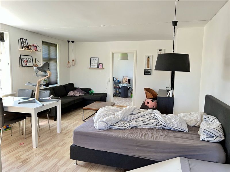 Moderne stue med højt loft, hvidt bord og stol, sort sofa med pude, kaffebord og lamper