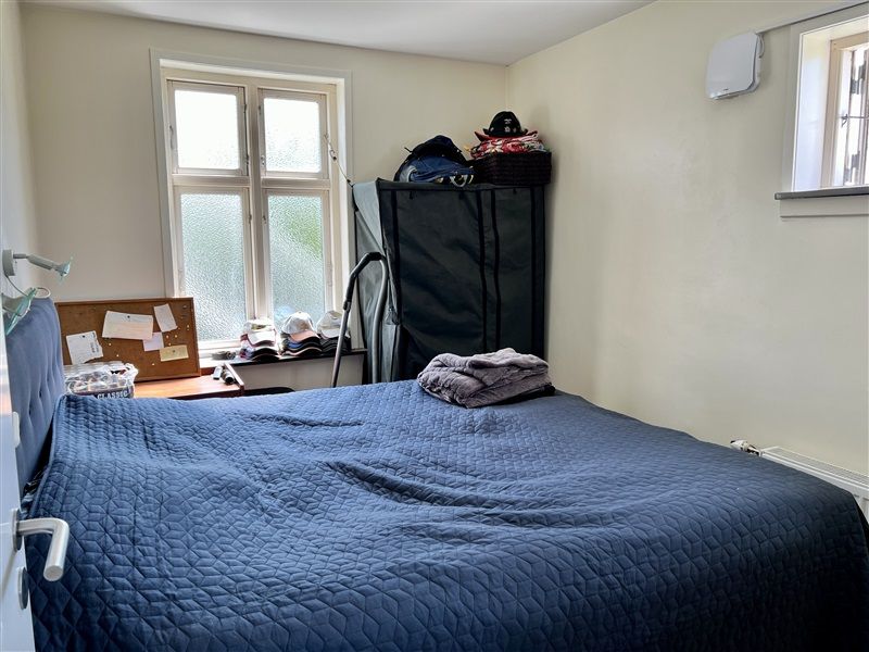 Et soveværelse med dobbeltseng, sengetøj og et klædeskab med mange ting og en kurv med tøj