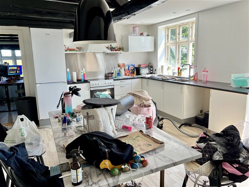 Udstyret køkken med flere ting spredt over skranken og en støvsuger rullede ud på gulvet