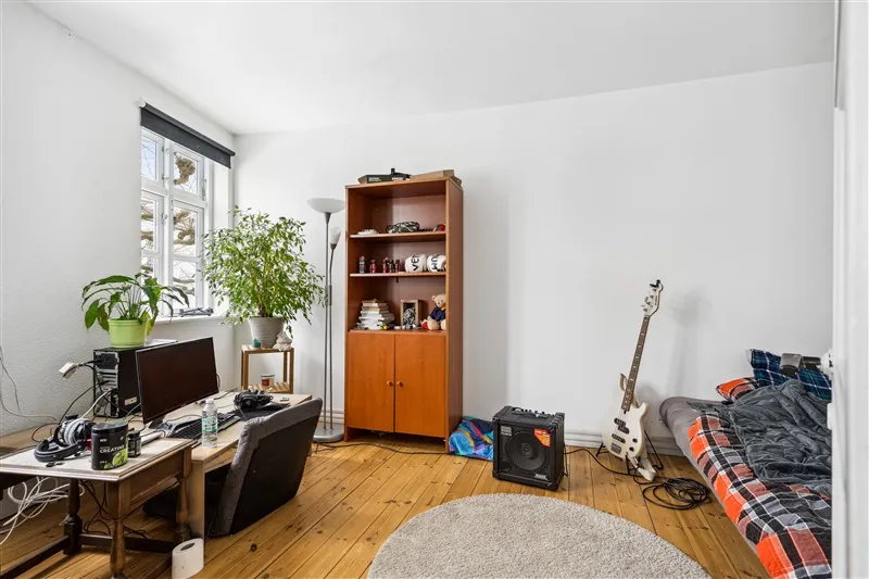 Soveværelse med brændenældeplante, elektronisk udstyr, musikinstrumenter, og trægulv.