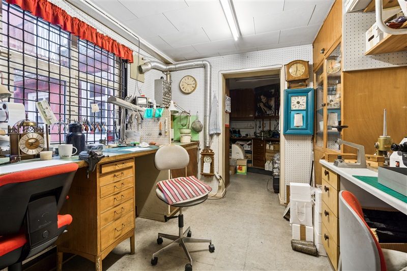 Møbelværksted med flere skriveborde og stole samt ure på væggen og loftet