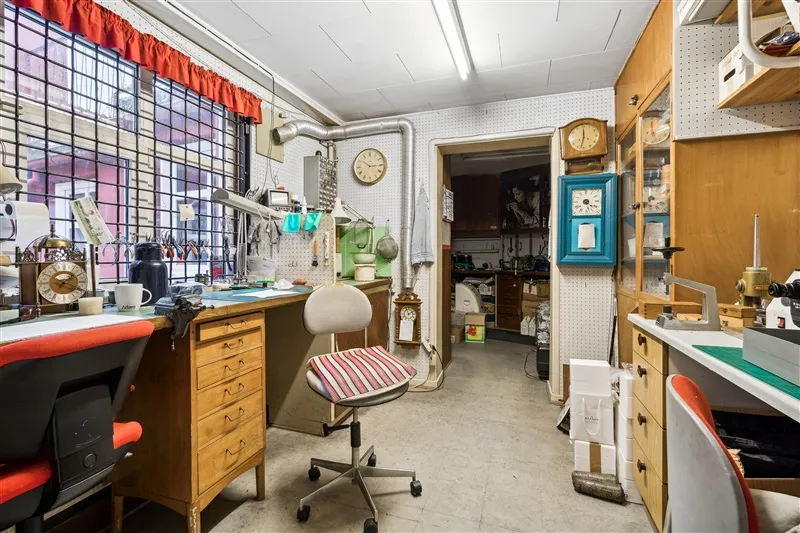 Møbelværksted med flere skriveborde og stole samt ure på væggen og loftet