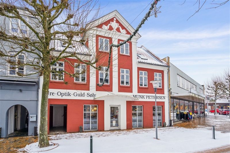 Oplysninger om optik- og guldforretning Munk Petersen i Ringe med snedækket og røde bygninger med hvide vinduerne