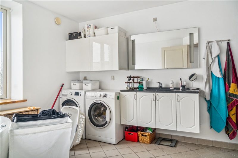 To vaskemaskiner og tørretumblere i et flotte lyse vaskeri med spejl og håndklæder i baggrunden