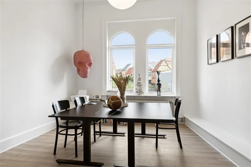 Møbelstilet spisebord med fire stole samt to basketballer og et vindue med udsigt til gaden