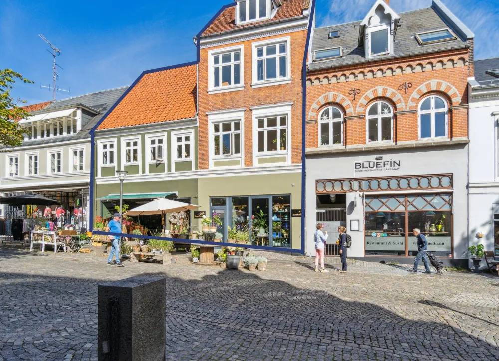Personer går på stenbrolægget gade, Bluefin restaurant og sushi, to personer går med tasker og en mand med en hvid parasol