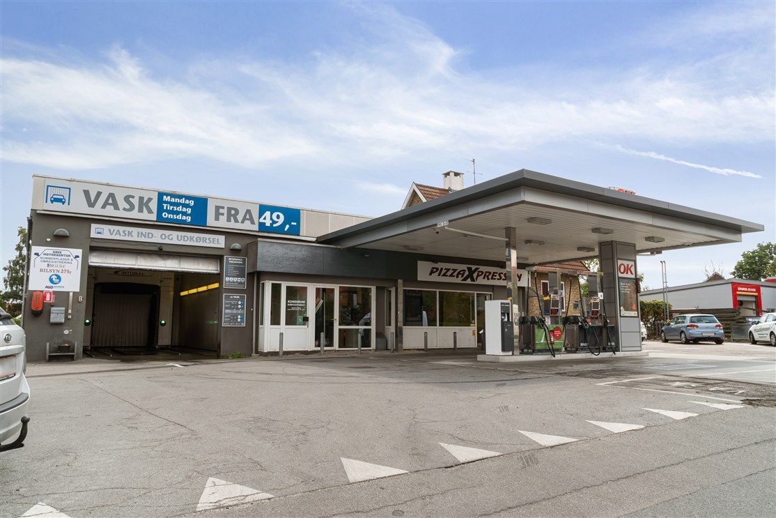 Et tankhus med forretning til vask og pizza. Der er en bilvask, og der er flere biler parkeret.