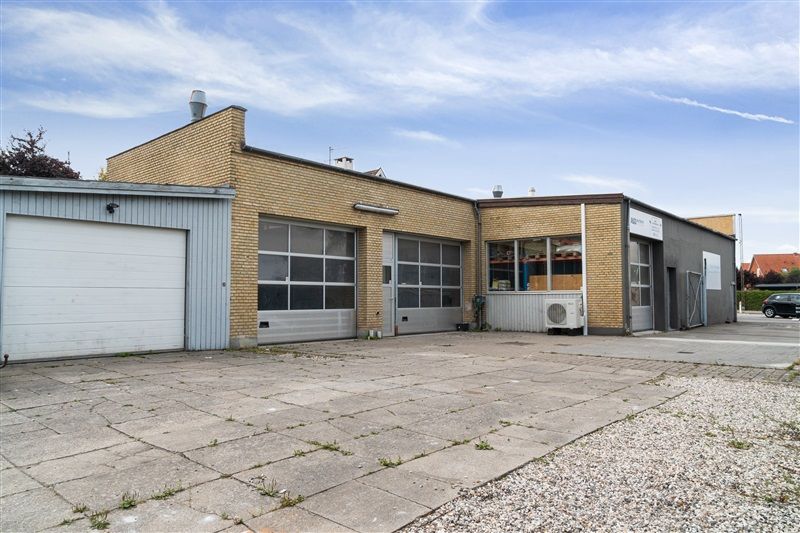 Et stort, gult hus med tre garagedøre og flere vinduer og et skilt på veggen