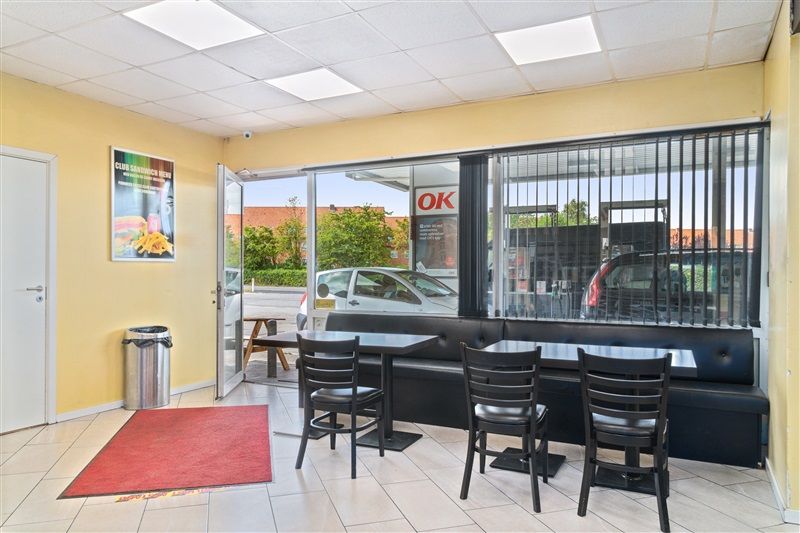 Udlejningsejendom med indgangsparti og serveringsområde med borde og stole. Der er en avis med menuen fra restauranten. Der