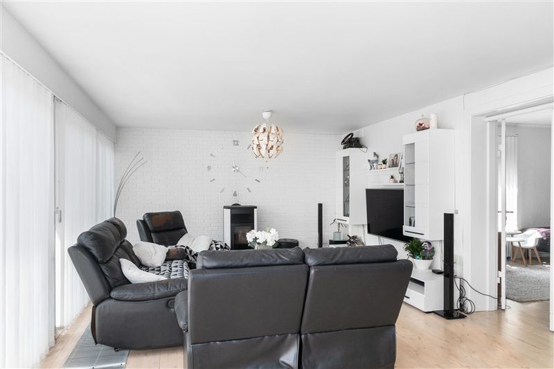 Lejlighed med lyse interiør, hvidt loft, gulv og vægge og moderne møbler som sort sofa, tv og højttalere