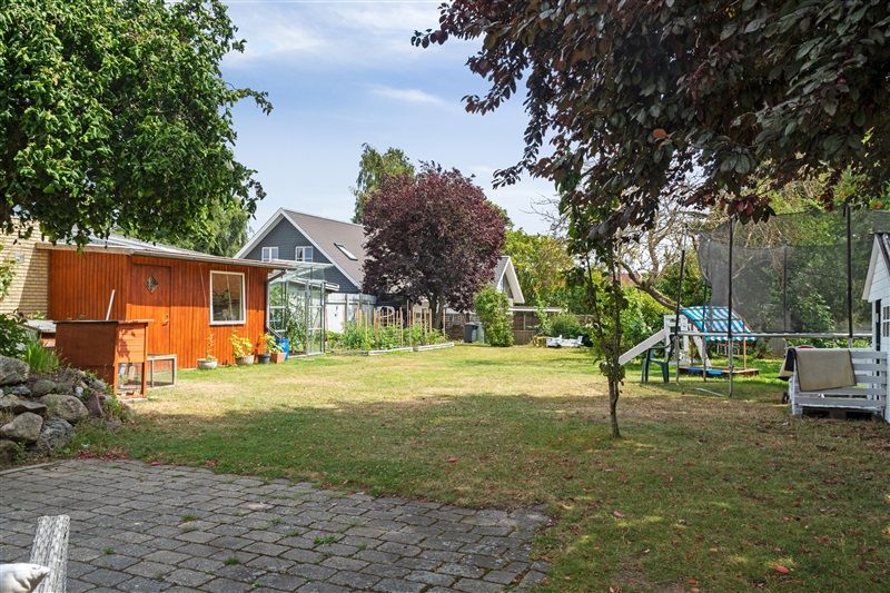 Her er et eksemplar på en have med græsplæne, trampoline, skur og træer