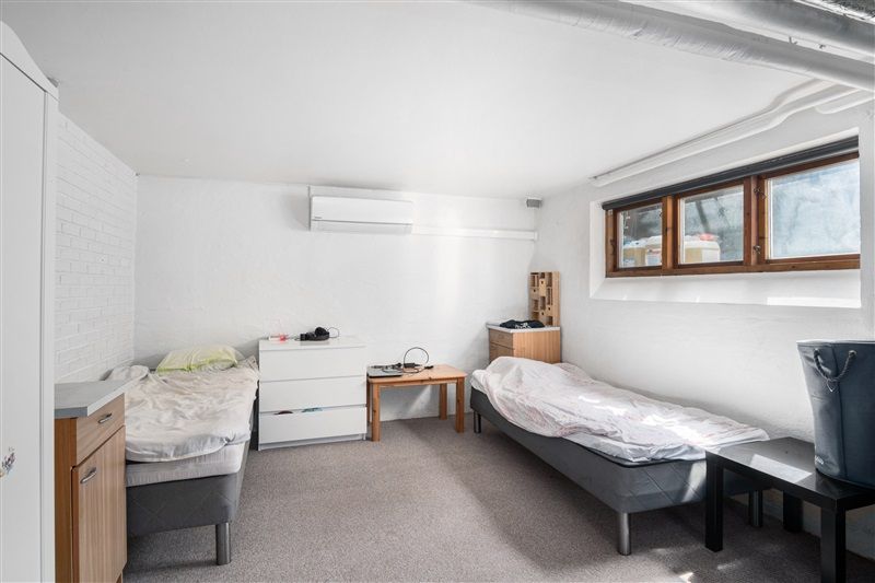 To soveværelser med hvide vægge og gulvtæppe samt hvide senge og træskabe i en lille lejlighed