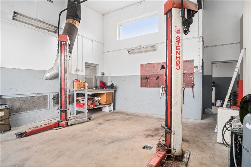 Garage med gulv og loft samt to stigelifte, redskaber og værktøj, samt åbne døre til siderum