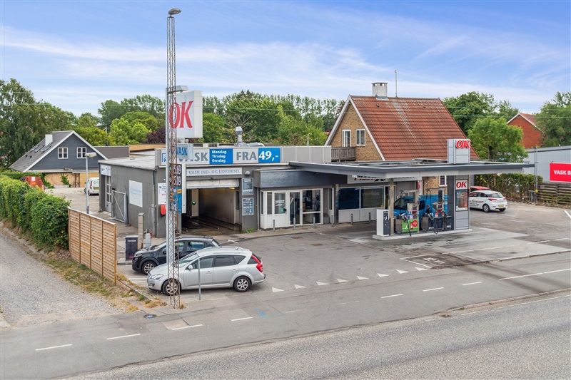 Køge med OK tankstation og biler parkeret ved siden af samt et lille hus i baggrunden