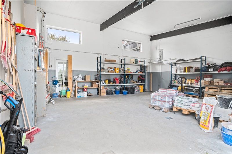 Garage med opbevaringsrum og diverse redskaber og materialer som skovle, slanger og beholdere