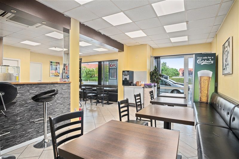 Afkast 8,09% Vordingborgvej 7, 4600 Køge. I lokalet er der bord, stol og sofa med et ølbanner i baggrunden