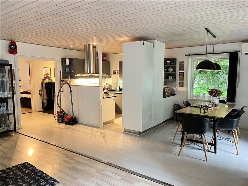 Modernt køkken med lyse lofter, hvide vægge og trægulv samt møbler og apparater