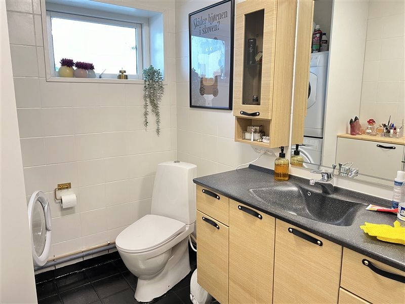 Et moderne badeværelse med en hvid toilet, en hængende kabinet og en ren hvid væg