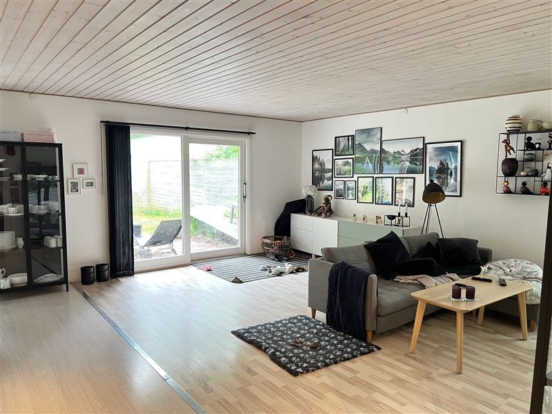 En stor stue med hvide vægge, massiv trægulv og højt loft, en stor sofa med tæpper og et træbord med to lysestager