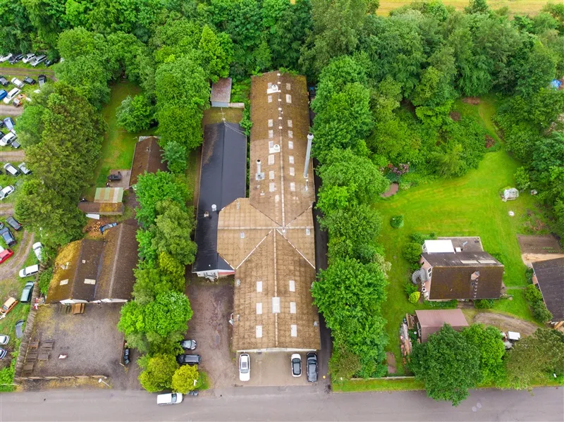 Fabrik i Them med parkeringsplads og flere biler og vogne parkeret udenfor samt grønne områder