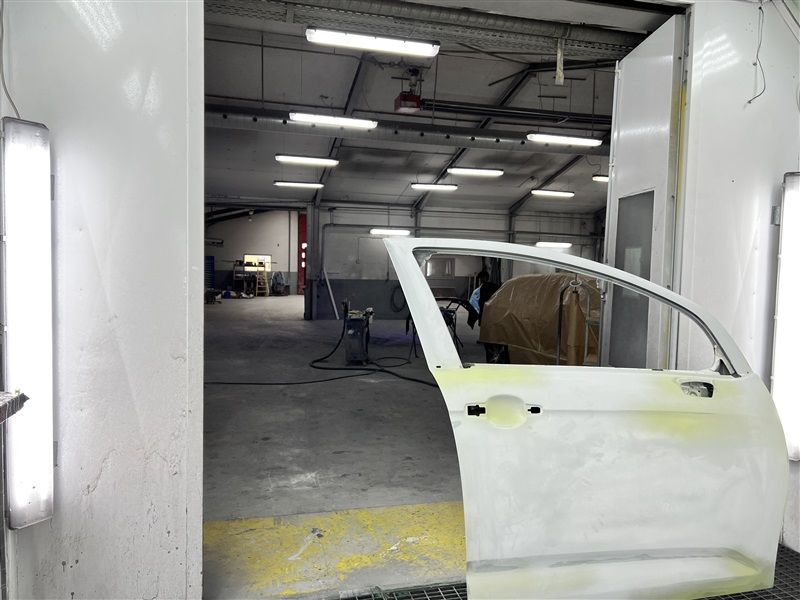 Bilport i produktionslokal med hvidt kabinet og lys i loftet samt gul gulv og mørk baggrund