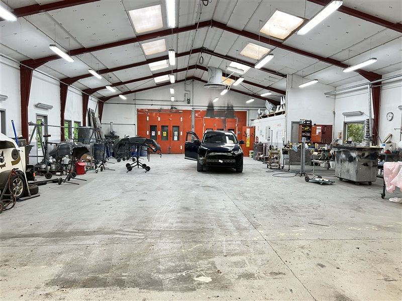 Garage med biler og værkstedsudstyr og lysekroner hængende fra loftet