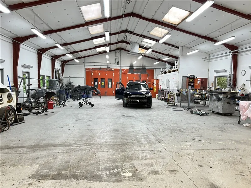 Garage med biler og værkstedsudstyr og lysekroner hængende fra loftet