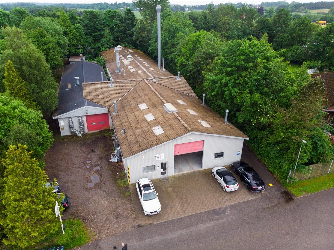 Erhvervsejendom med parkeringsplads og bilgarager og biler parkeret udenfor fabrikken