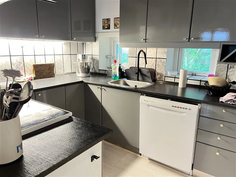 Alt om rødt og hvidt i denne moderne køkken med glat sort urtavle, hvid maskine og lysegrå skabe