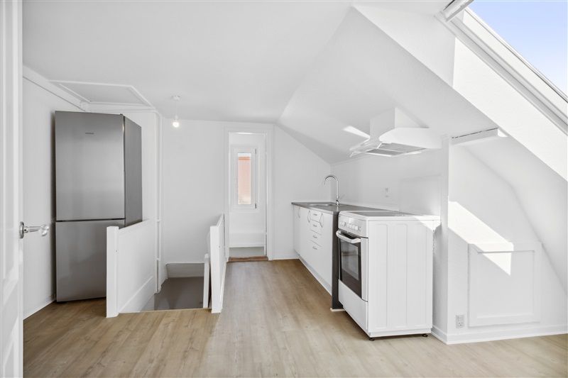 En stor køkken med lyse vægge og hvide skabe samt et køleskab og en ovn