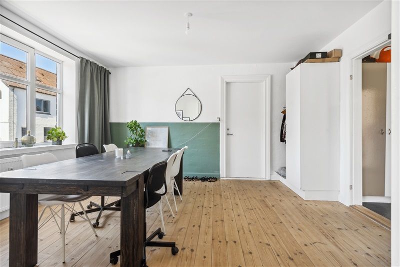 Smukke møbler og plante i et moderne og minimalistisk indrettet værelse med lyse trægulve og en stor vinduesfordybelse