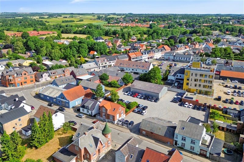 En smuk dansk by med mange huse og biler i parkeringspladsen foran byens centrum