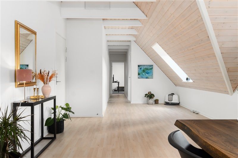 Foto af moderne bolig med højloft og massivt træloft, møbler og indretning i lyse nuancer, slanke plantekrukker og spejl med