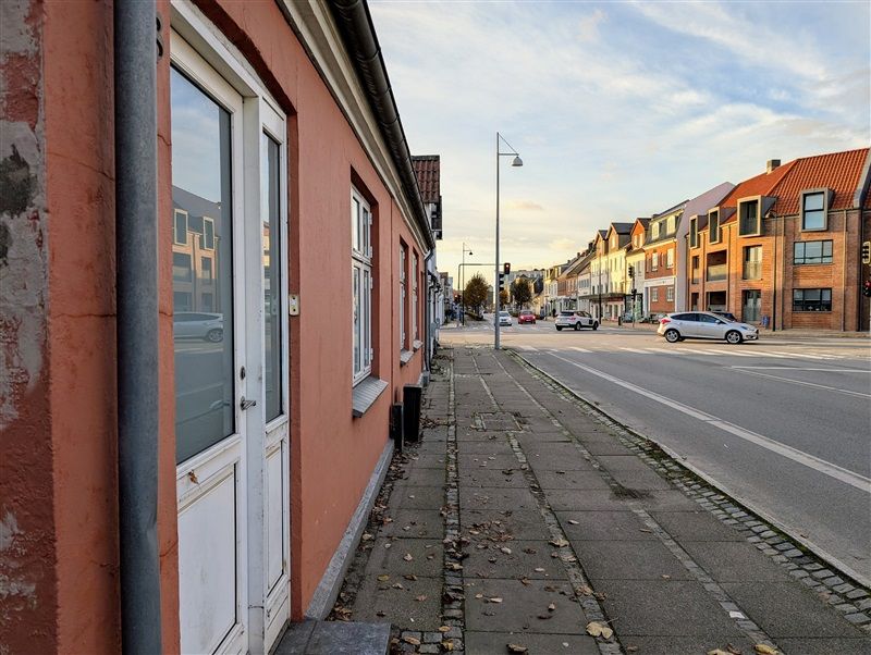 Middelfart byvej med moderne og røde bygninger og biler kører forbi på vejen