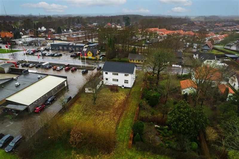 En smuk gård med store huse og parkeringsplads med biler og flag, der står på vejen